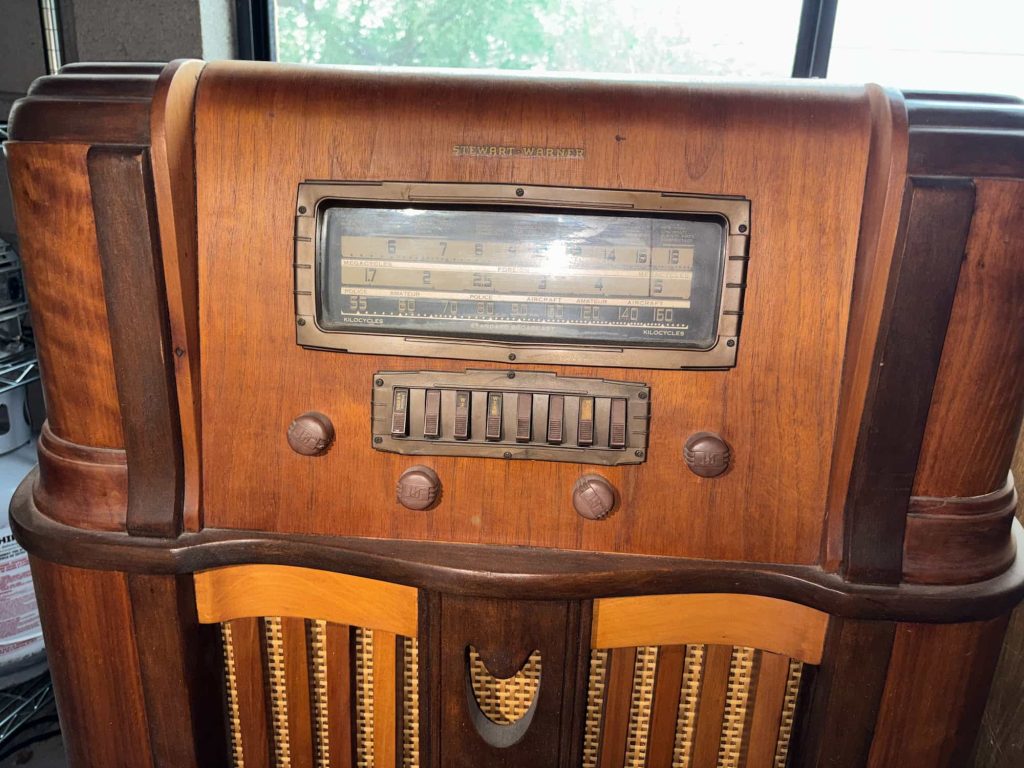 Antique wooden tube radio console with push-button controls, glass tuning display, and classic speaker grille