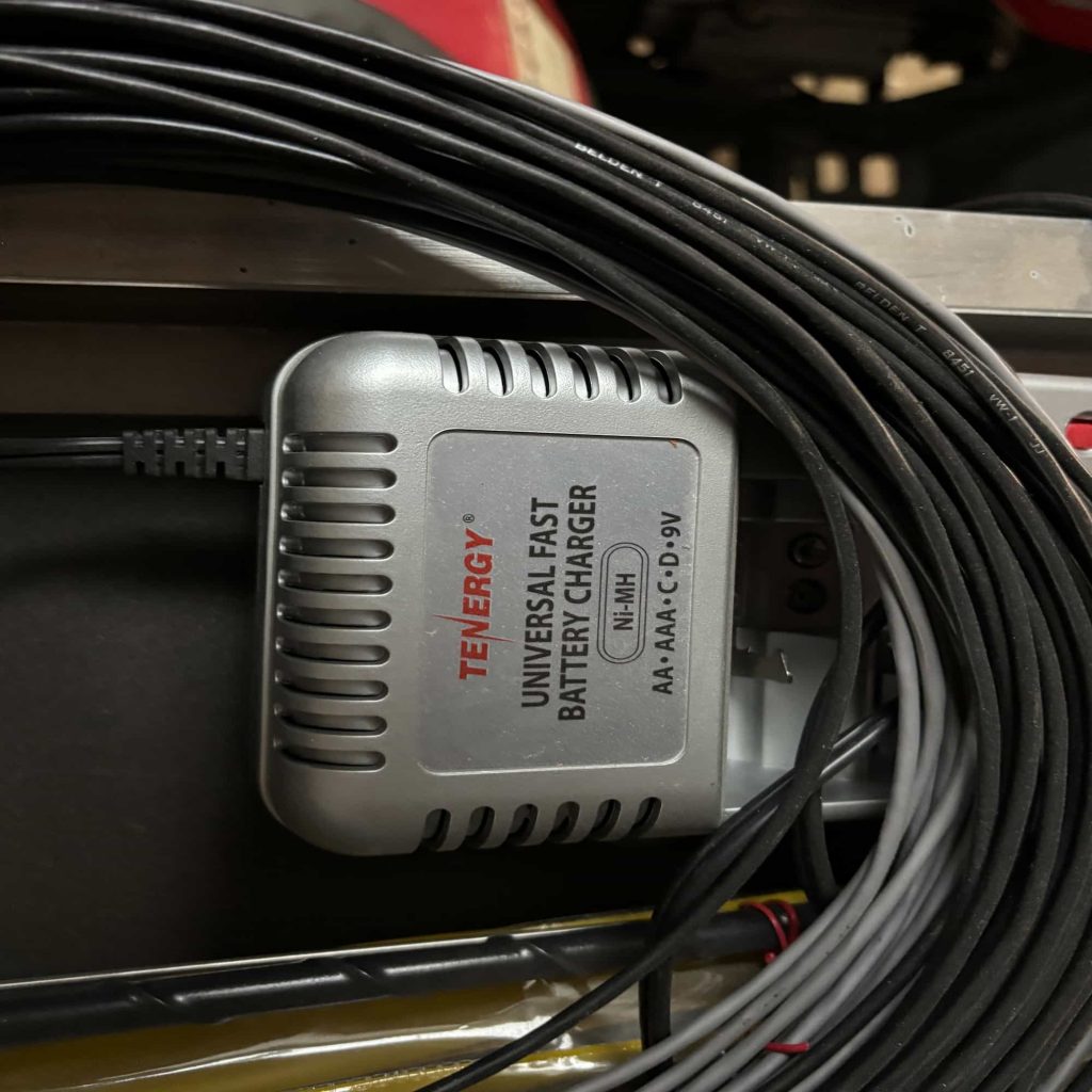 Silver Tenergy Universal Fast Battery Charger for Ni-MH AA, AAA, C, D, and 9V batteries, partially surrounded by coiled black Belden cables.