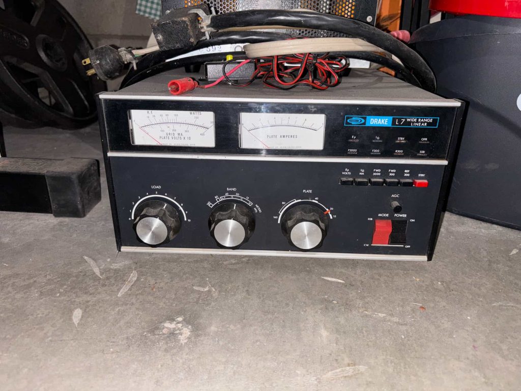 Vintage radio equipment with dials and meters on a concrete floor. Two analog gauges display readings. Knobs and switches enhance a retro feel.