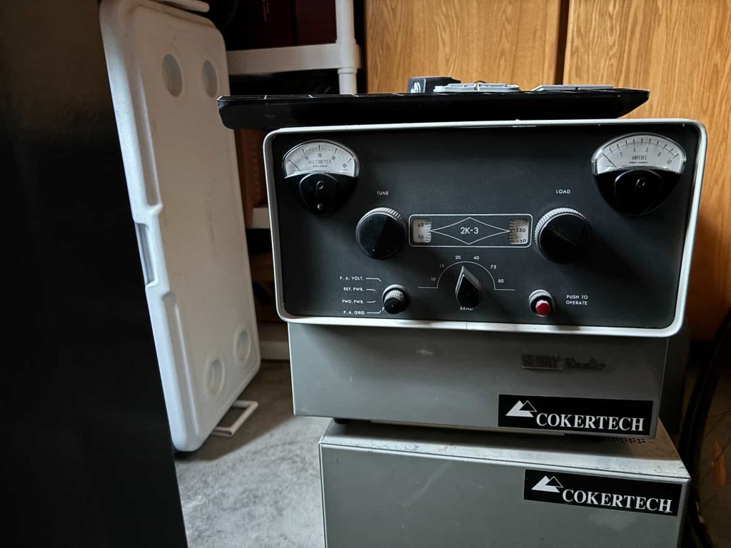 Vintage electronic equipment with analog dials and knobs labeled "2K-3" and "COKERTECH," set in a dimly lit room with wooden cabinets.
